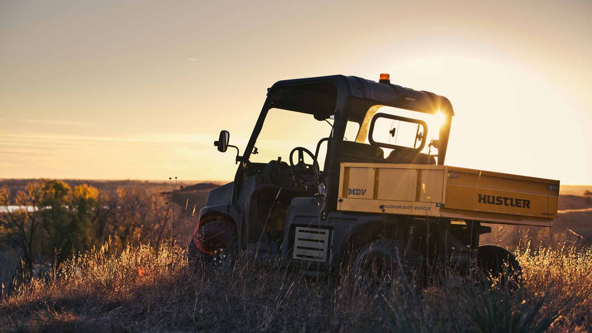 A tractor is parked in a field at sunset