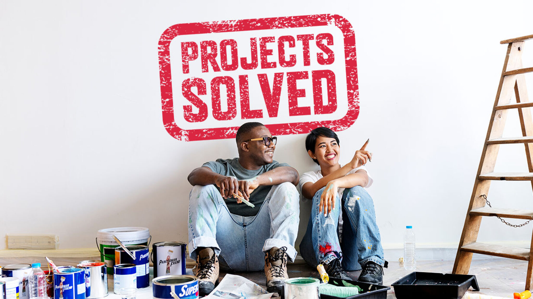 a couple sitting on the floor in front of a wall with a project's solved stamp on it